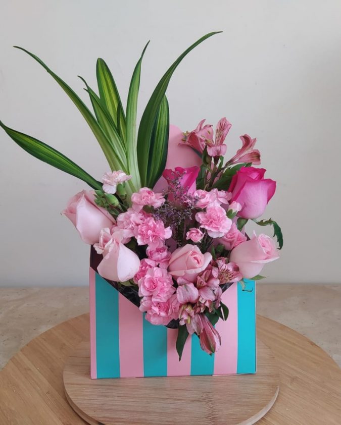 Arreglo florar sobre azul turquesa con rosa